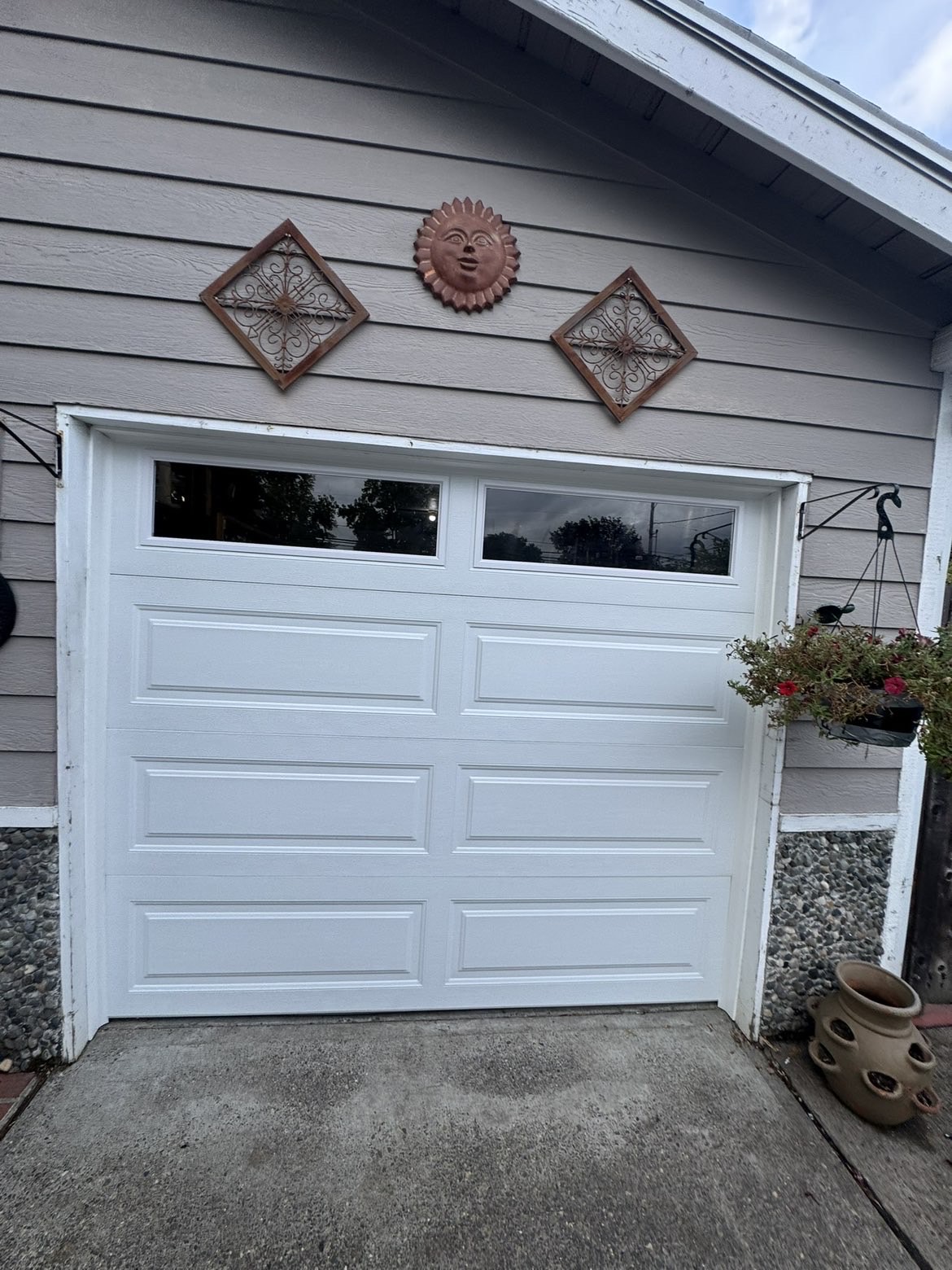 White long-panel garage door with window row on a grey home