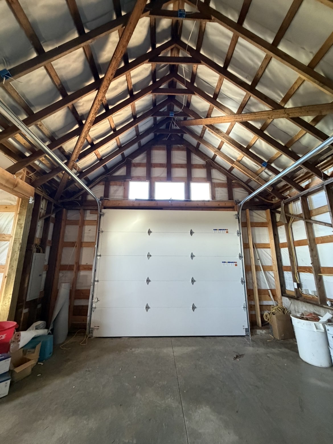 Interior view of a new white garage door installed in a timber-framed shop