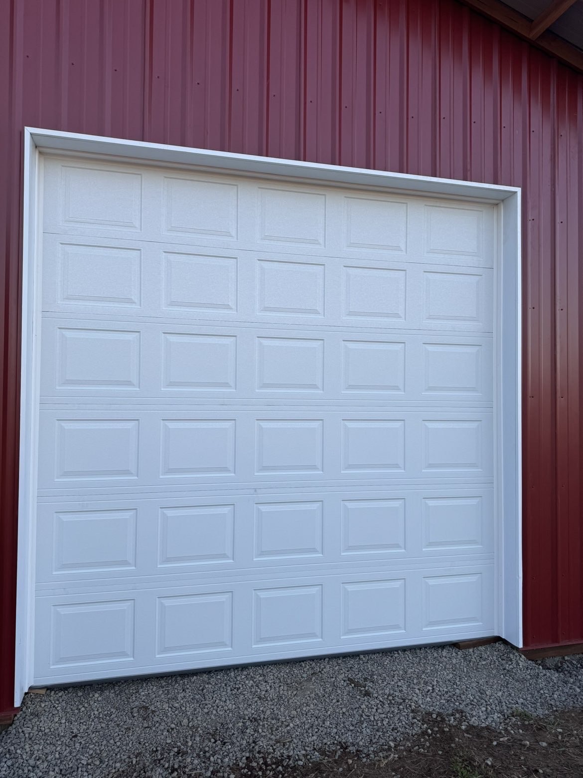 White short-panel garage door on a red metal pole barn