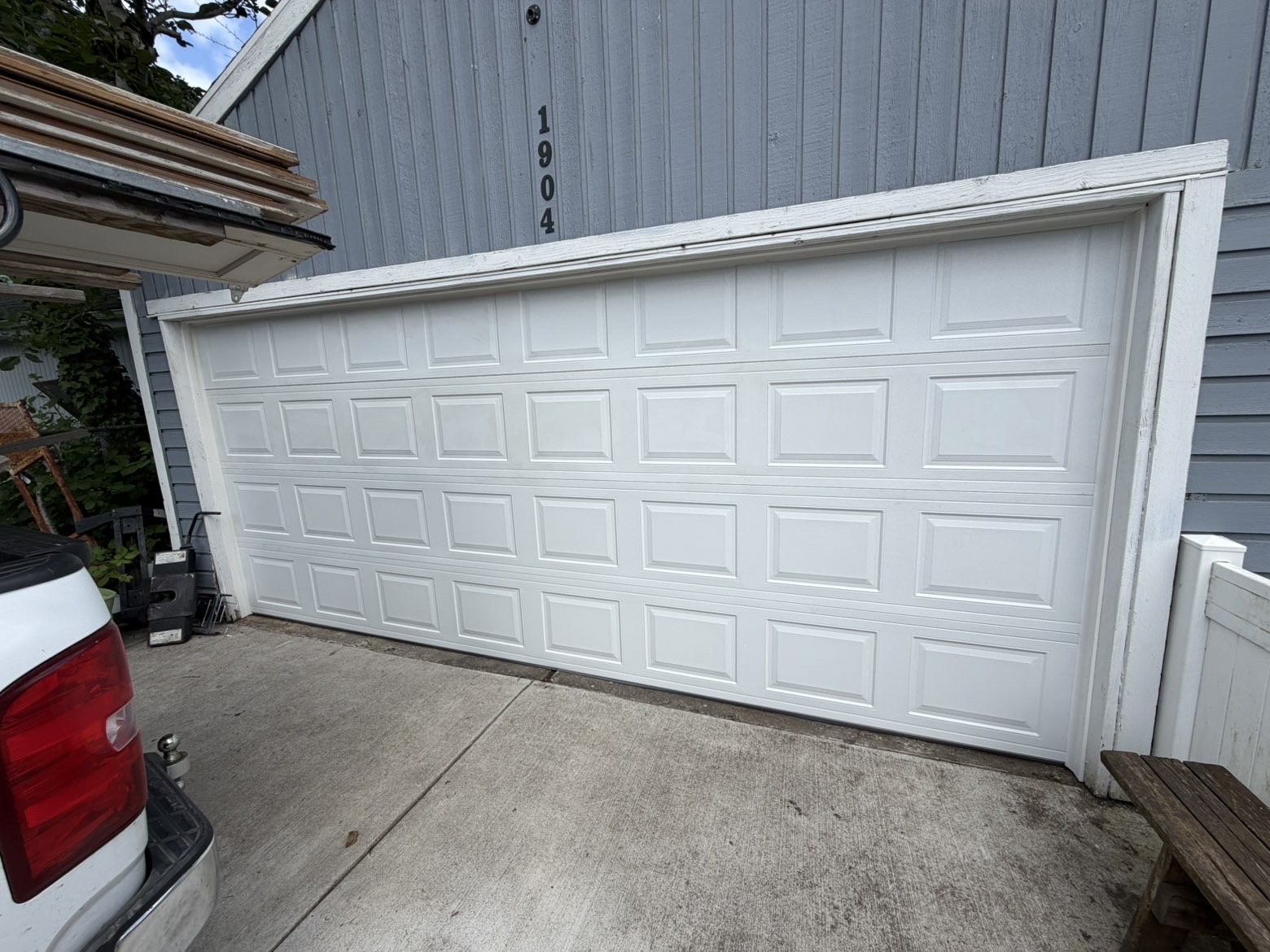 Wide white short-panel double garage door on a blue home