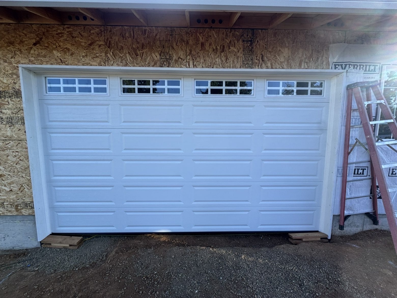 White long-panel double garage door with windows on new construction